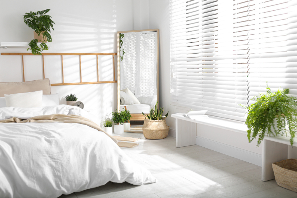 dormitor in stil scandinav cu oglinda in coltul camerei si plante verzi